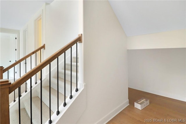 stairway featuring hardwood / wood-style flooring and lofted ceiling