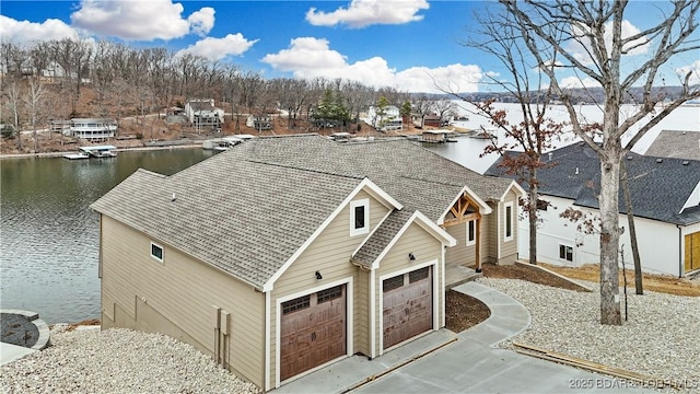 view of front of house featuring a water view, a garage, concrete driveway, and roof with shingles