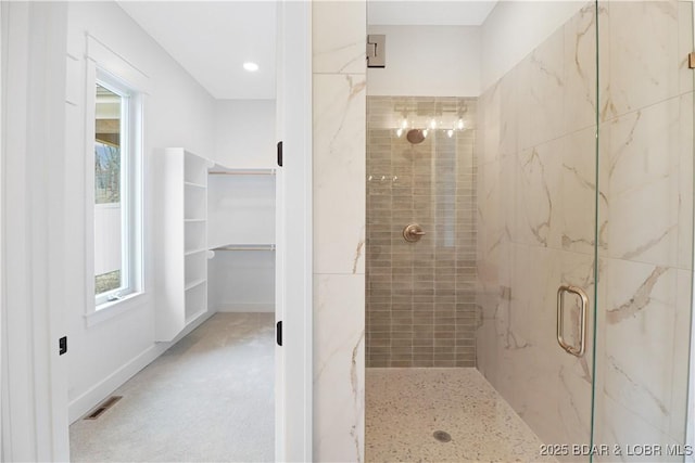 bathroom featuring a wealth of natural light, a walk in closet, visible vents, and a marble finish shower