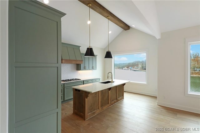 kitchen with an island with sink, sink, hanging light fixtures, custom exhaust hood, and stainless steel gas cooktop