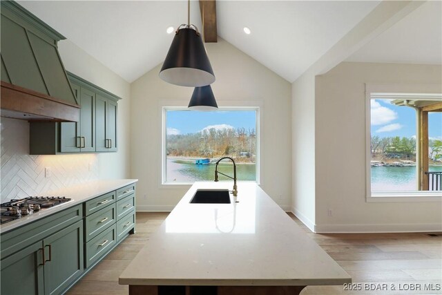 kitchen with premium range hood, sink, stainless steel gas cooktop, a water view, and pendant lighting