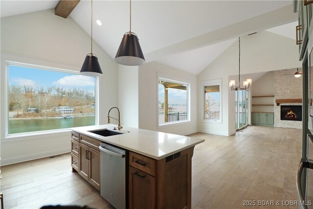 kitchen featuring sink, a water view, dishwasher, an island with sink, and pendant lighting