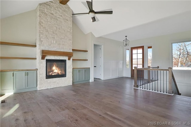 unfurnished living room with hardwood / wood-style flooring, a stone fireplace, high vaulted ceiling, and ceiling fan