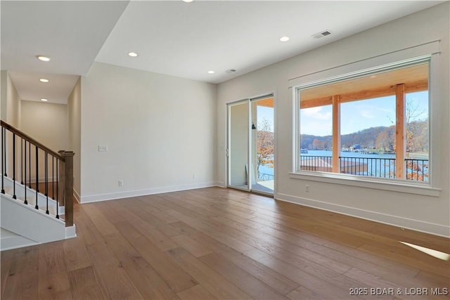 unfurnished room with hardwood / wood-style flooring and a water view