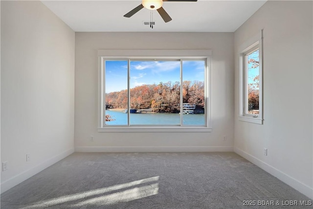 unfurnished room featuring carpet, ceiling fan, and a water view