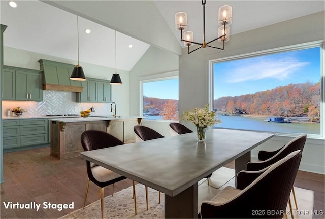 dining room with dark wood finished floors, a notable chandelier, recessed lighting, a water view, and vaulted ceiling