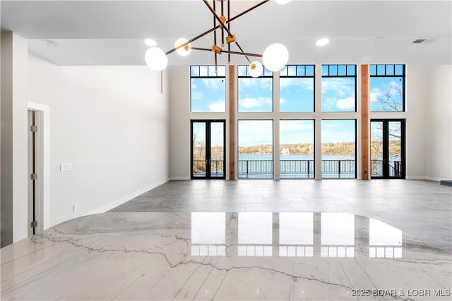 unfurnished room featuring a water view, a towering ceiling, and an inviting chandelier