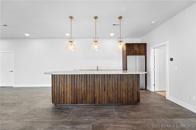 kitchen with pendant lighting, stainless steel fridge, and a center island with sink