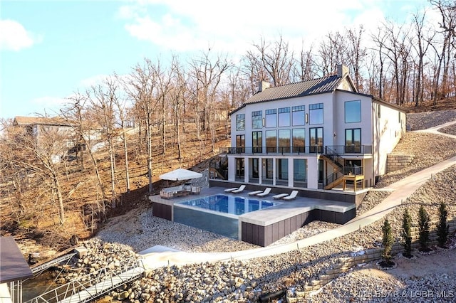 back of property with a hot tub and a patio area