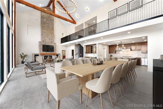 dining area featuring an inviting chandelier, a fireplace, beamed ceiling, and a high ceiling