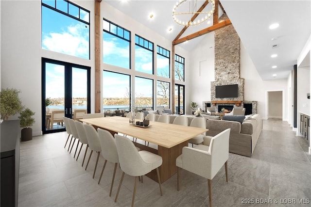 dining space featuring a notable chandelier, a wealth of natural light, a fireplace, and french doors