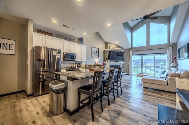 kitchen with stone counters, white cabinetry, a breakfast bar area, a center island, and stainless steel appliances