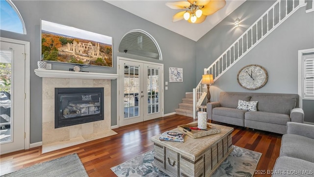 living room with a premium fireplace, dark hardwood / wood-style floors, high vaulted ceiling, and french doors