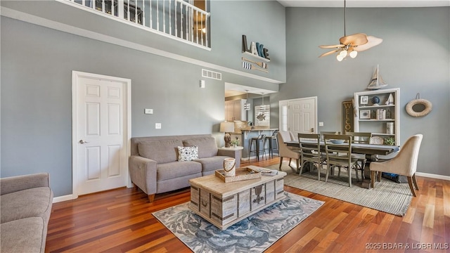 living room featuring hardwood / wood-style floors, a towering ceiling, and ceiling fan