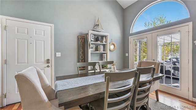 dining room featuring a towering ceiling, french doors, and light wood-type flooring