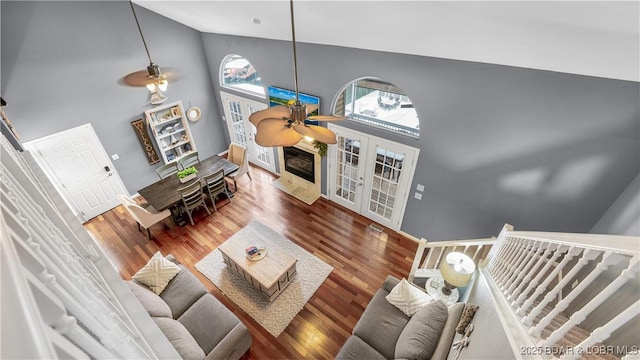 living room with a premium fireplace, dark hardwood / wood-style flooring, ceiling fan, and high vaulted ceiling