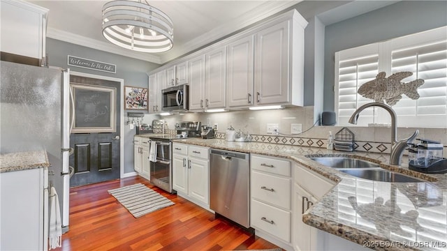 kitchen with sink, white cabinetry, tasteful backsplash, appliances with stainless steel finishes, and hardwood / wood-style flooring