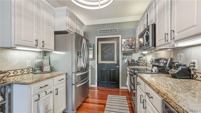 kitchen featuring crown molding, appliances with stainless steel finishes, dark hardwood / wood-style floors, light stone counters, and white cabinets