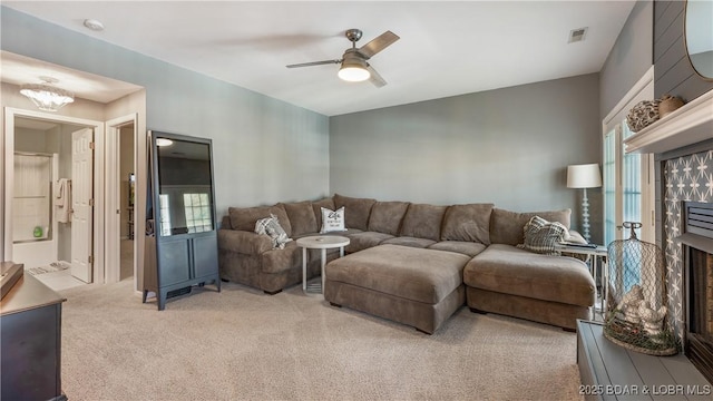 carpeted living room with ceiling fan with notable chandelier and a high end fireplace