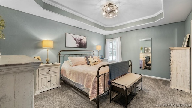 carpeted bedroom with ornamental molding and a tray ceiling