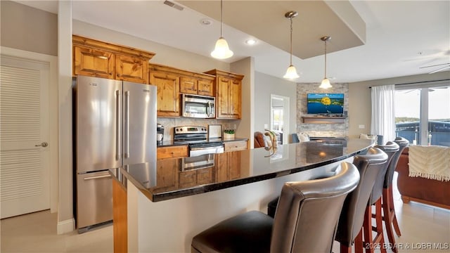 kitchen featuring light tile patterned flooring, tasteful backsplash, appliances with stainless steel finishes, a kitchen breakfast bar, and a kitchen island