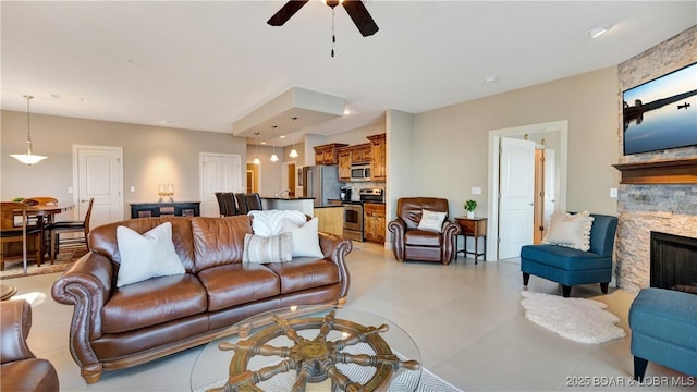 living room featuring a stone fireplace and ceiling fan