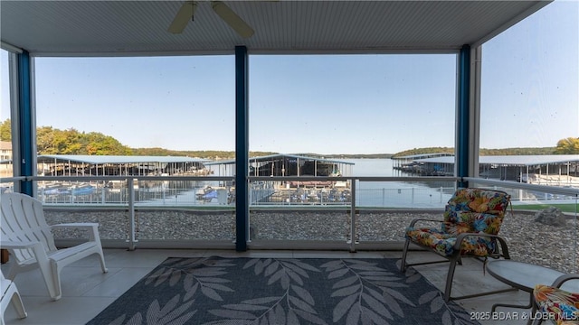 sunroom with ceiling fan and a water view