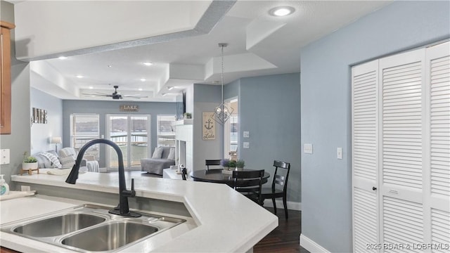 kitchen with sink, dark hardwood / wood-style flooring, a raised ceiling, pendant lighting, and ceiling fan