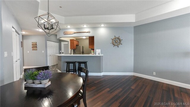 dining area with dark hardwood / wood-style flooring, a notable chandelier, and sink