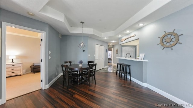 dining room featuring sink, a tray ceiling, and dark hardwood / wood-style floors