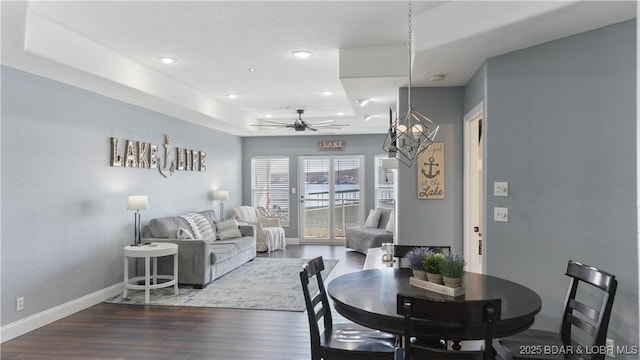 dining space with ceiling fan, a tray ceiling, and hardwood / wood-style floors