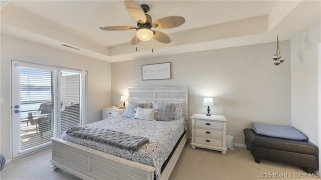 bedroom featuring access to outside, light carpet, ceiling fan, and a tray ceiling