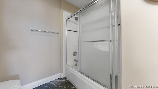 bathroom featuring bath / shower combo with glass door and toilet