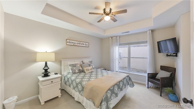 carpeted bedroom featuring ceiling fan and a tray ceiling