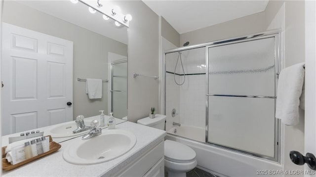 full bathroom with enclosed tub / shower combo, vanity, and toilet