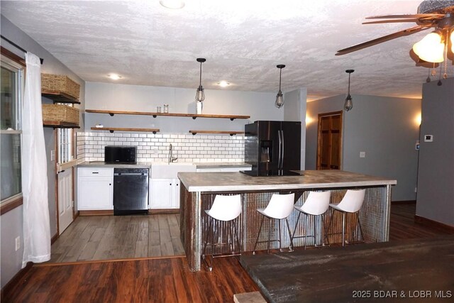 747 Paulson Dr, Edwards, MO 65326 - kitchen with dark hardwood / wood-style flooring, white cabinets, a kitchen breakfast bar, and black appliances
