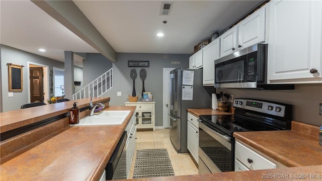 kitchen with white cabinetry, appliances with stainless steel finishes, sink, and light tile patterned floors