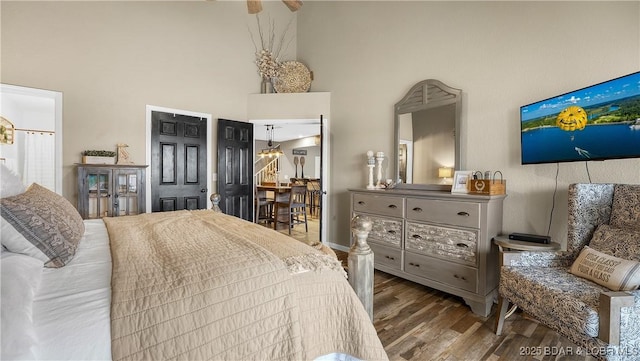 bedroom featuring hardwood / wood-style flooring and a towering ceiling