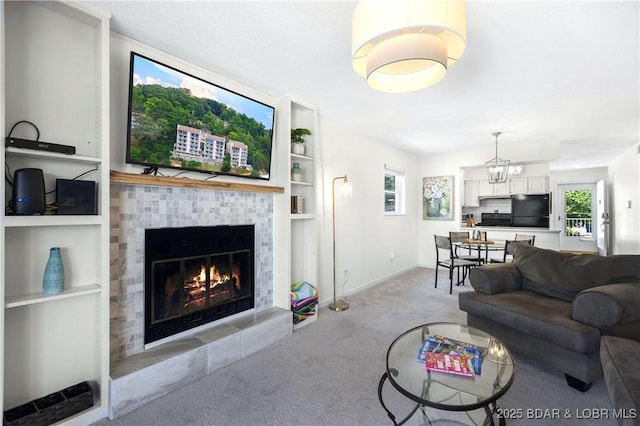 living room with a tiled fireplace, light carpet, an inviting chandelier, and built in shelves