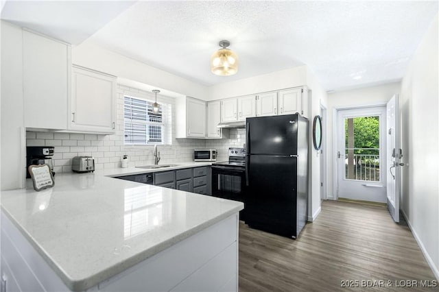 kitchen with sink, black appliances, kitchen peninsula, and white cabinets