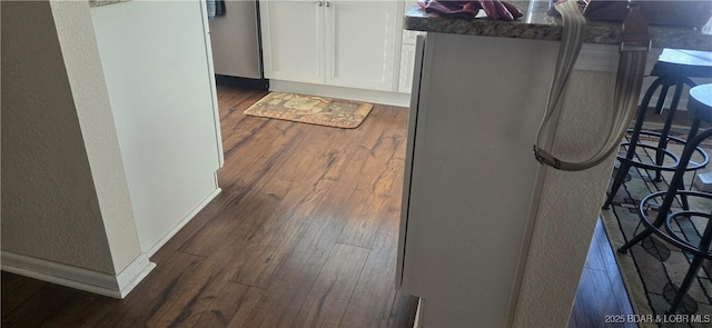 room details with white cabinetry, dark wood-type flooring, and a kitchen bar