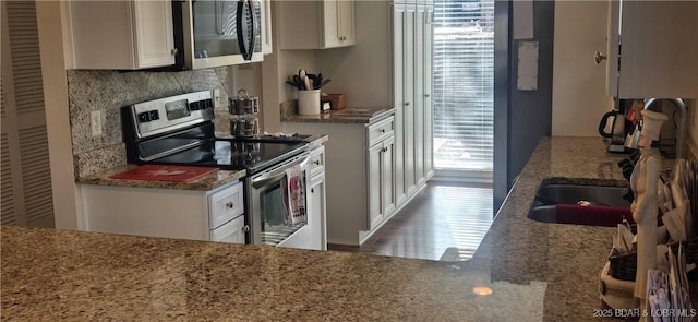 kitchen featuring sink, wood-type flooring, white cabinets, stainless steel appliances, and backsplash