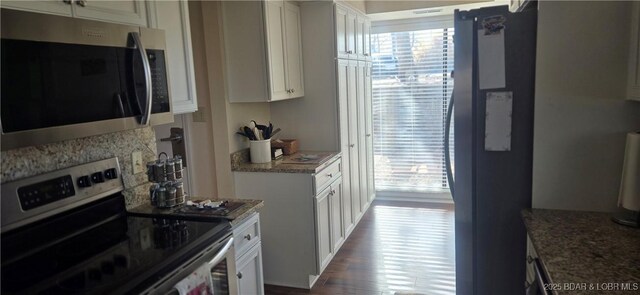 kitchen featuring white cabinets, appliances with stainless steel finishes, dark hardwood / wood-style flooring, and backsplash