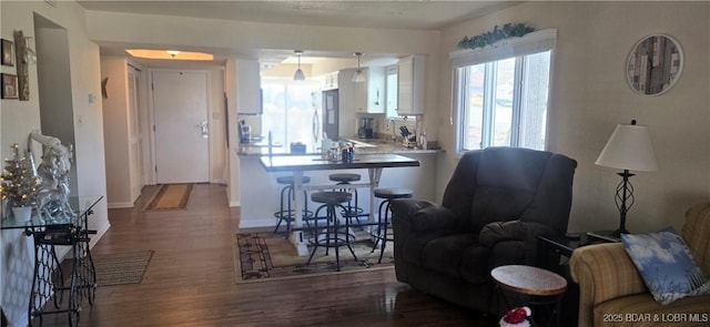 kitchen featuring stainless steel refrigerator, white cabinetry, a kitchen breakfast bar, dark hardwood / wood-style flooring, and kitchen peninsula