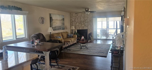 living room featuring ceiling fan, dark wood-type flooring, and a fireplace