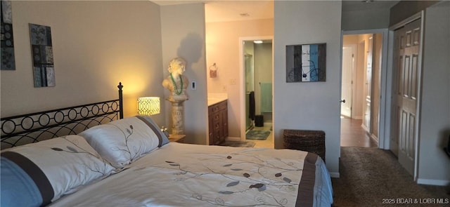 carpeted bedroom with a closet, ensuite bathroom, and baseboards