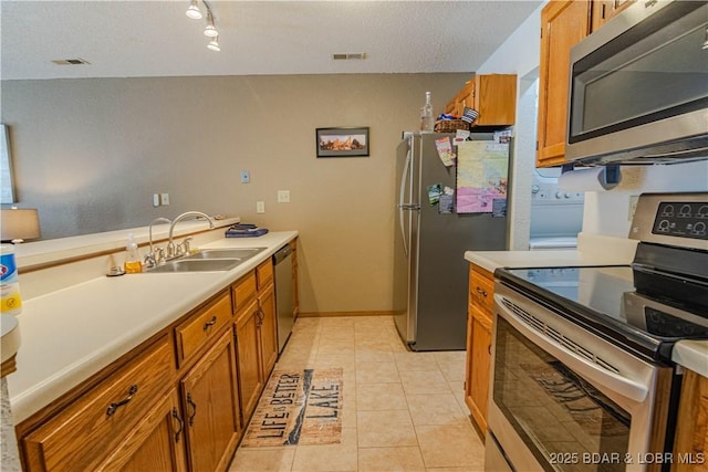 kitchen featuring sink, light tile patterned floors, stainless steel appliances, and a textured ceiling