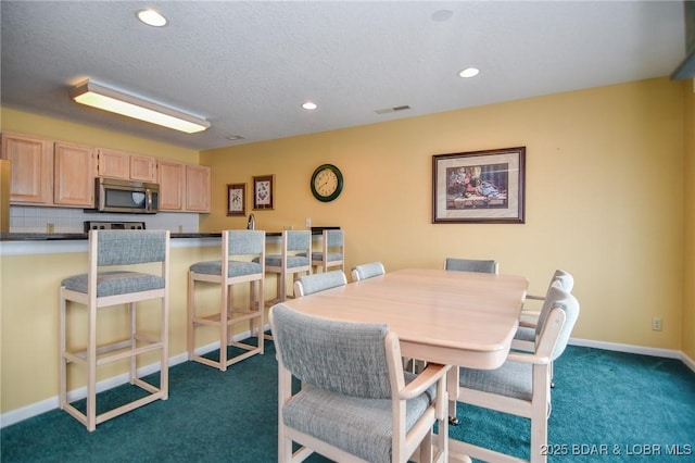 dining area featuring a textured ceiling and dark colored carpet