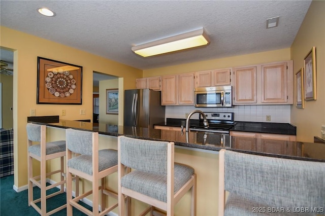 kitchen with stainless steel appliances, a kitchen breakfast bar, decorative backsplash, and light brown cabinets