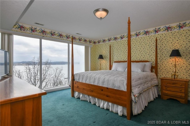 bedroom featuring a water view, access to exterior, and dark carpet